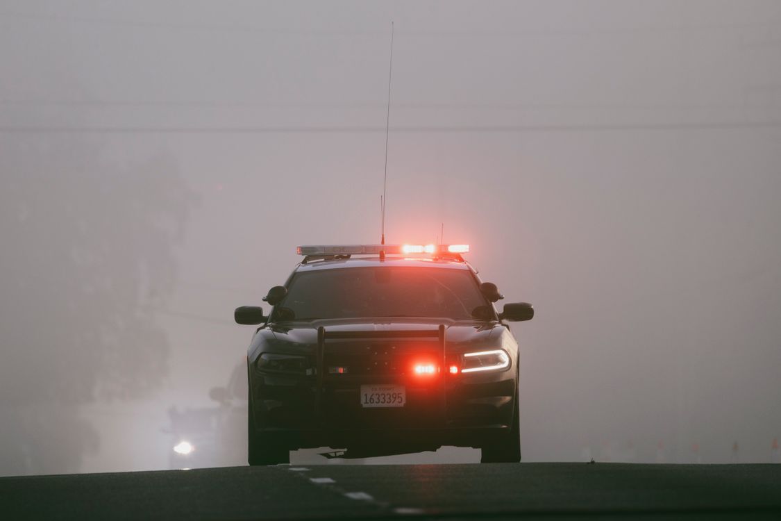 Patrol vehicle with emergency lights on a foggy road
